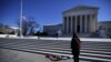 Flowers are seen as a woman stands in front of the Supreme Court building in Washington, D.C., after the death of U.S. Supreme Court Justice Antonin Scalia, Feb. 14, 2016.