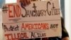 FILE - An anti-immigration protestor holds a sign in front of his face as he demonstrates in front of NBC Studios, Nov. 4, 2015. 