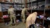 Seorang pengungsi asal Afghanistan tampak mencari sepatu yang disumbangkan bagi para pengungsi di sebuah pusat donasi di pangkalan militer Fort McCoy di Wisconsin, pada 30 September 2021. (Foto: Pool via AP/Barbara Davidson)