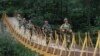FILE - Indian Border Security Force soldiers patrol over a footbridge built over a stream near the Line of Control, a cease-fire line dividing Kashmir between India and Pakistan, at Sabjiyan sector of Poonch district, August 2013.