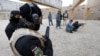 A German police officer guards an Afghan National Police trainee as she fires her weapon at a training center in Mazar-e-Sharif, northern Afghanistan, December 18, 2012. 