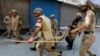 Indian policemen carry their injured colleague after he was wounded during a protest in Srinagar July 18, 2013. 