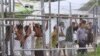 FILE - Asylum-seekers look through a fence at the Manus Island detention center in Papua New Guinea, March 21, 2014. 