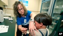 La enfermera registrada Starr Roden, coordinadora de acercamiento a la comunidad en el departamento de salud de Knox County, pone una vacuna a Jonathan Detweiler, un niño de 6 años en Mont Vernon, Ohio. Foto del 17 de mayo de 2019.