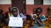 FILE - A young displaced Muslim girl holds a sign saying “No to Violence” at a displaced persons site, the Catholic church in Bangassou, Central African Republic.