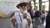 A voter poses for a photo with her inked finger after casting her ballot inside a polling station during the presidential elections in Algiers, Algeria, Sept. 7, 2024.