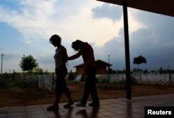 FILE - A deaf-blind woman (R) is led by a caregiver at Santa Angela de la Cruz Center in Salteras, near Seville, Spain, June 6, 2011.