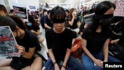 香港反送中示威者2019年8月12日在香港国际机场静坐示威时用黑布蒙眼，抗议警方一天前与示威者的冲突中使一名抗议者眼睛受伤。