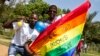 Des hommes ougandais brandissent un drapeau arc-en-ciel: "Rejoignez-nous pour mettre fin au génocide LGBTI (Lesbian Gay Bi Trans Intersex - appelé Kuchu en Ouganda)", comme ils le célèbrent, le 9 août 2014.
