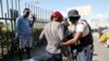 Seorang petugas polisi memeriksa seorang pengendara motor di titik pemeriksaan di Port-au-Prince, Haiti, pada 26 Januari 2024. (Foto: AP/Odelyn Joseph)