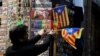 A shop keeper displays Catalan separatist "Estelada" flags next to souvenirs for tourists at a shop in Barcelona, Dec. 22, 2017. 