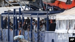 Des migrants se tiennent sur le pont du navire de sauvetage Humanity 1, géré par l'organisation allemande SOS Humanitarian, dans le port de Catane, en Sicile, dans le sud de l'Italie, dimanche 6 novembre 2022. (AP Photo/Salvatore Cavalli)