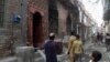 Residents look at a house of a family belonging to the Ahmadi sect, which was torched by angry mob in Gujranwala, Pakistan, July 28, 2014.