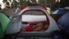 Decenas de migrantes que esperan en suelo mexicano mientras Estados Unidos procesa su solicitud de asilo acamparon en uno de los puentes internacionales que conectan con Brownsville, en Texas.