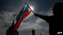 Seorang pria mengibarkan bendera nasional Rusia di Lapangan Merah di pusat kota Moskow menjelang Hari Rusia pada 11 Juni 2023. (Foto: AFP)