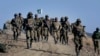 FILE - Pakistani troops walk on a hilltop post near Ladha, a town in the troubled Pakistani tribal region of Waziristan along the Afghan border.