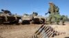 Một người lính Israel đi cạnh xe chở quân có vũ trang ở miền nam Israel gần biên giới với Dải Gaza vào ngày 30/11/2023, khi lệnh ngừng bắn giữa Israel và Hamas bước sang ngày thứ bảy.