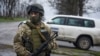 FILE - A Ukrainian soldier guards OSCE observers near the village of Shyrokyne, eastern Ukraine, April 19, 2015. 
