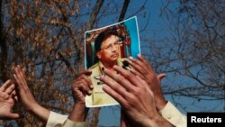 A supporter holds a picture of former Pakistani President Pervez Musharraf, during a protest with others at the Special Court where Musharraf will attend his trial in Islamabad, Feb. 18, 2014. 