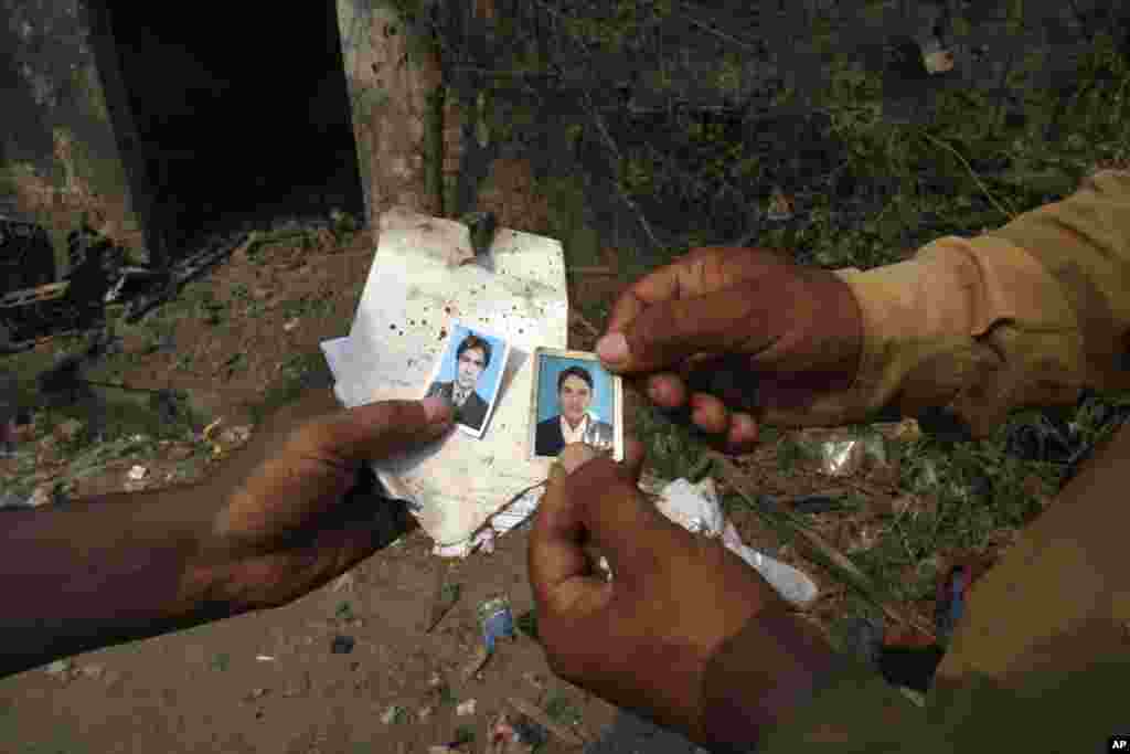 Men show passport pictures they found at the site of a bomb blast, Peshawar, Pakistan, Sept. 27, 2013.