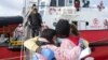 Seorang migran memeluk anggota LSM saat turun dari kapal penyelamat Open Arms, di Pelabuhan Augusta, Sisilia, setelah diselamatkan di laut, Sabtu, 12 Maret 2022. (Foto: AP)