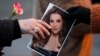 FILE: Seorang penggemar musik menyerahkan foto Lisa Marie Presley kepada penggemar lain saat menghadiri peringatan publik untuknya, satu-satunya putri "Raja Rock 'n' Roll," Elvis Presley, di Graceland Mansion di Memphis, Tennessee, AS 22 Januari 2023. 9REUTERS/Nikki Boertman)