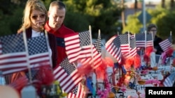 FILE - A couple looks over 58 wooden crosses, with the names and photos of the Oct. 1 mass shooting victims, in the median of Las Vegas Boulevard South near the "Welcome to Las Vegas" sign in Las Vegas, Nevada, Oct. 9, 2017.