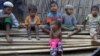 In this March 17, 2017, image made from video, Rosmaida Bibi, center foreground, suffering from severe malnutrition, sits on a pile of bamboo trees with other children at the Dar Paing camp, north of Sittwe, Rakhine state, Myanmar.