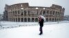 A man stands in front of the ancient Colosseum blanketed by the snow in Rome, Feb. 26, 2018. 