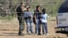 FILE - A Border Patrol agent stands on a ranch fence line with children taken into custody in South Texas brush country north of Laredo, Texas.
