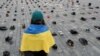 Seorang perempuan menatap ratusan sepatu yang melambangkan kejahatan perang yang dilakukan terhadap warga sipil Ukraina di Alun-alun Kota Tua untuk memperingati satu tahun invasi Rusia ke Ukraina, di Praha, Republik Ceko, 15 Februari 2023. (Foto: REUTERS/David W Cerny)